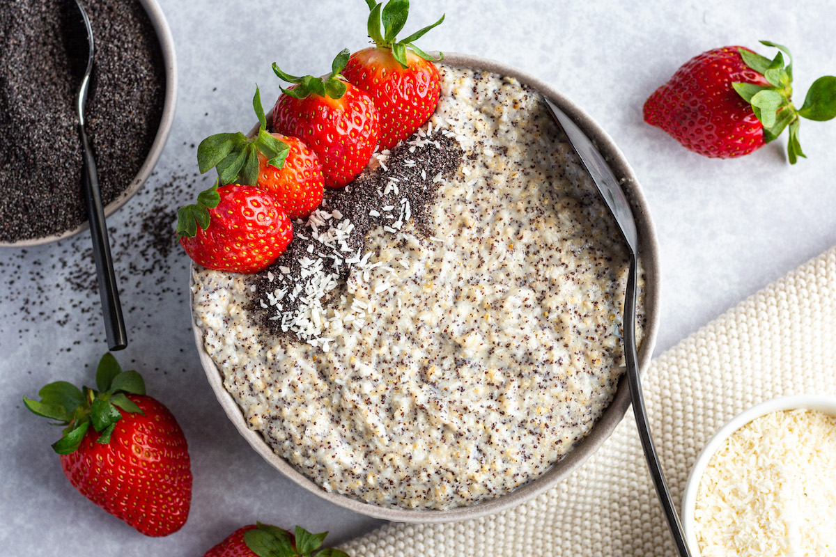 Mohn-Kokos-Porridge in einer Schüssel. Mit Erdbeeren und Dampfmohn dekoriert.