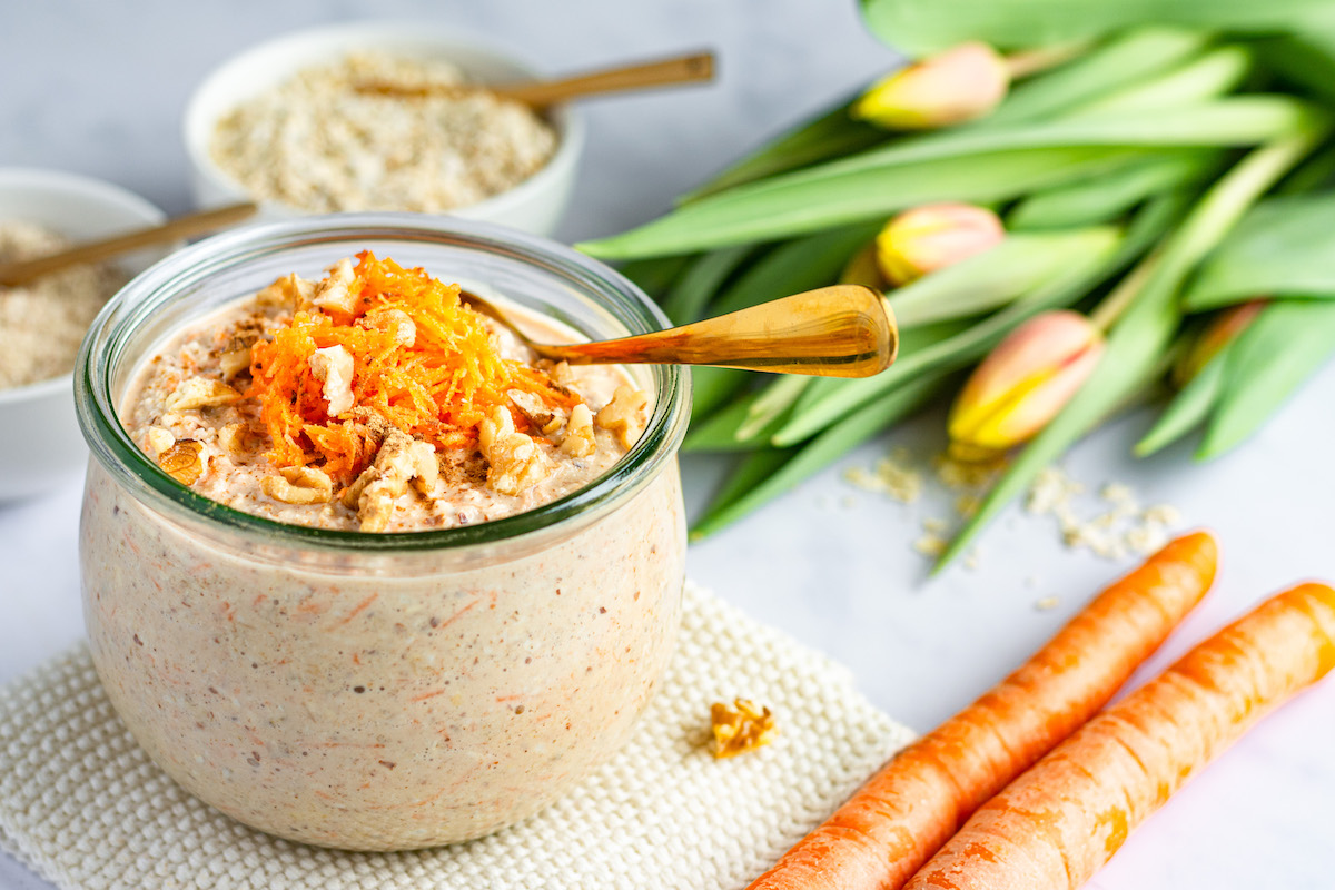 Carrot Cake Overnight Oats in ein Glas gefüllt und mit geraspelten Karotten dekoriert.