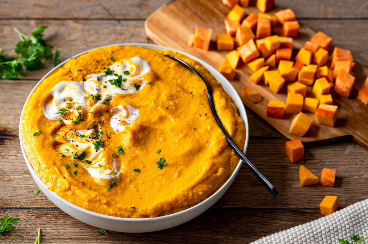 Kürbis-Süßkartoffel-Suppe Kürbis-Süßkartoffel-Suppe in einer Schüssel serviert und mit Petersilie dekoriert.
