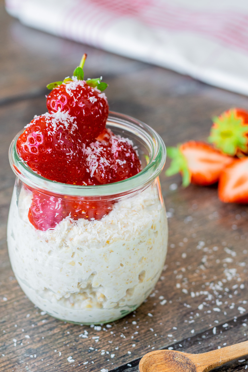 Overnight Oats mit Joghurt in ein Weckglas gefüllt und mit frischen Erdbeeren dekoriert.