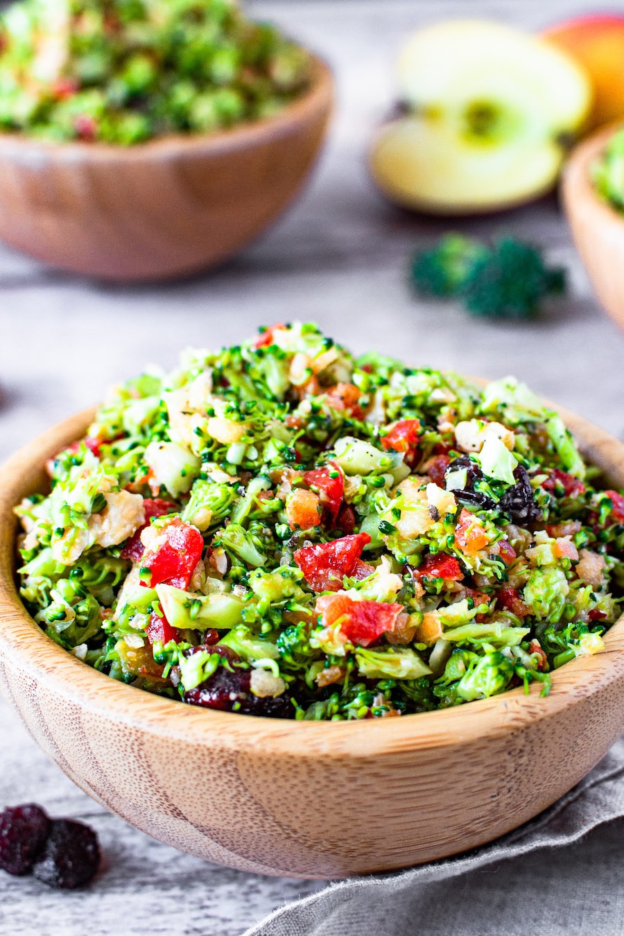 Roher Brokkoli-Salat mit Apfel, Paprika, Walnüssen und Cranberries in einer kleinen Holzschüssel serviert.