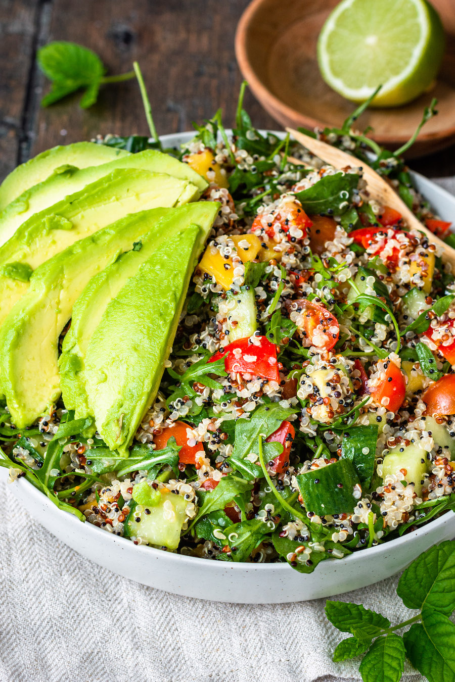 Teller mit Quinoa-Salat mit Avocado, Gurke, Tomaten, Paprika, Minze und Limette