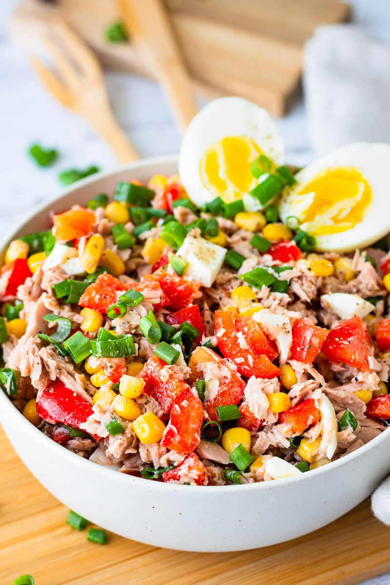 Thunfisch-Salat mit Paprika und Mais in einer Schüssel, mit gekochten Eierhälften dekoriert