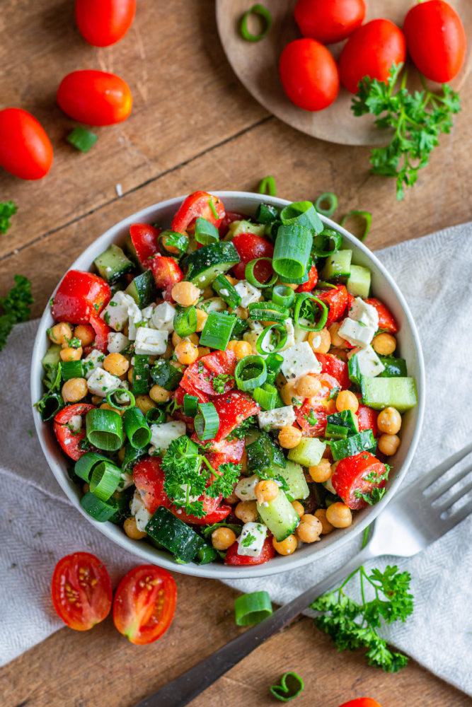 Kichererbsen-Salat in einer Schüssel, außenherum sind Tomaten und Petersilie dekoriert.