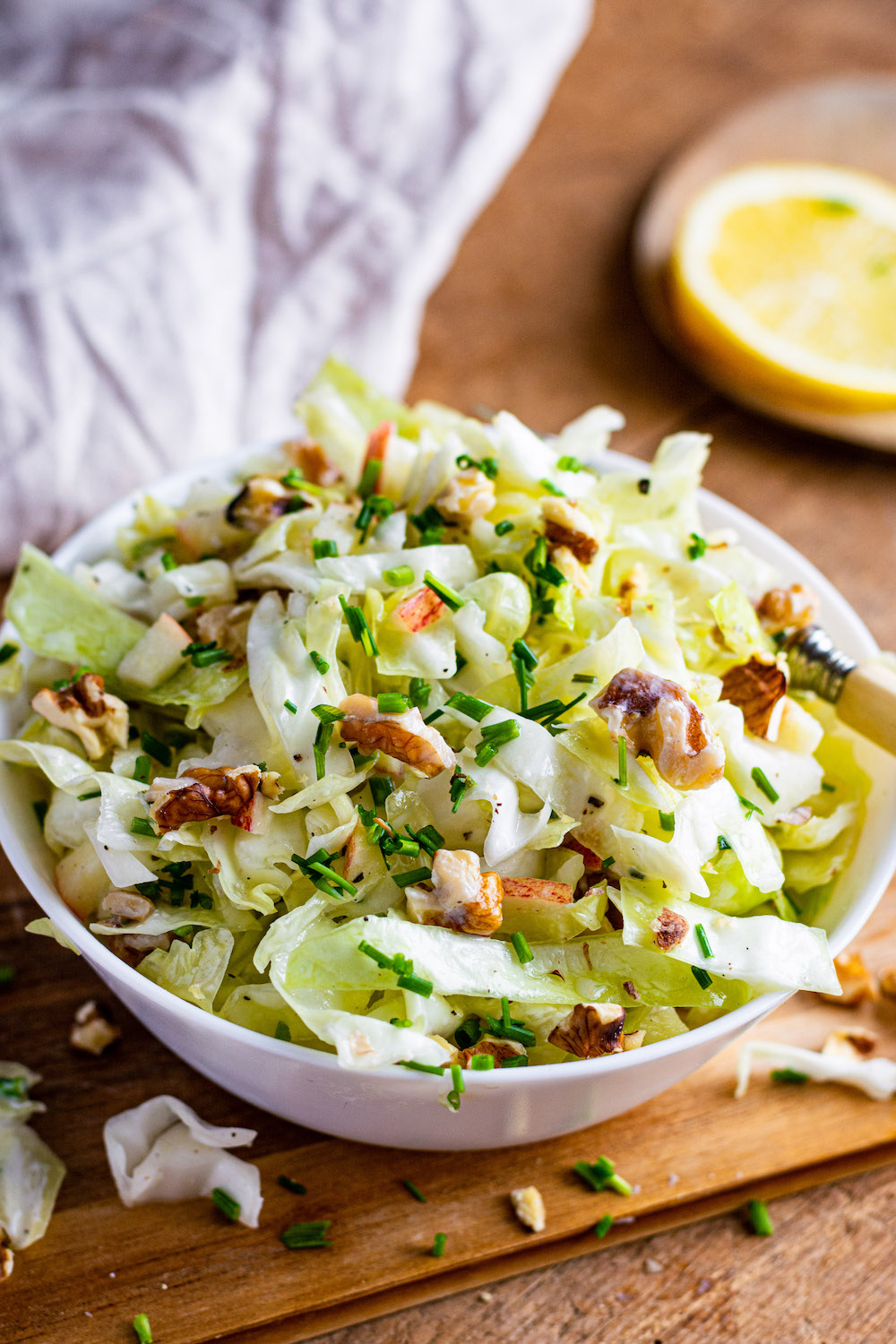 Salat aus Spitzkohl, Apfel und Walnüssen in einer Schüssel, in welcher eine kleine Gabel steckt.