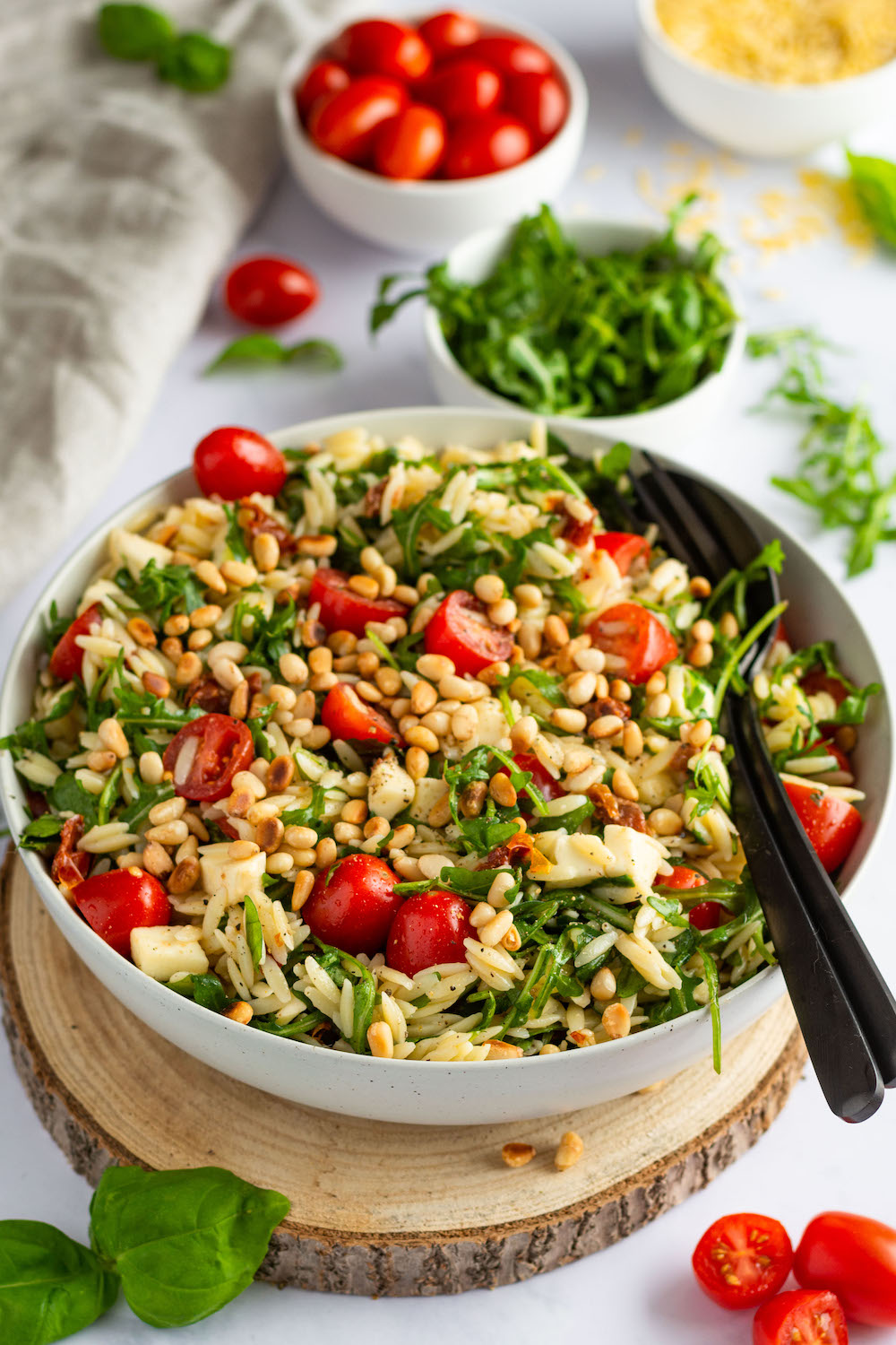 Risoni-Salat mit Tomaten, getrockneten Tomaten, Rucola und Mozzarella mit Pinienkernen bestreut.