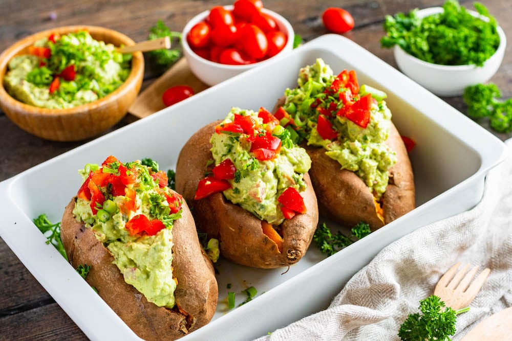 Drei mit Avocado-Creme gefüllte Süßkartoffeln in einer Auflaufform.