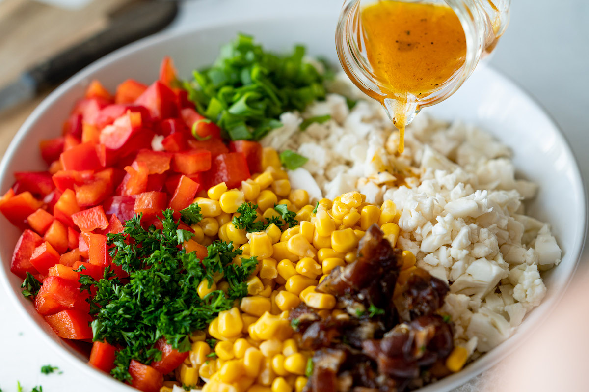 Dressing wird über Zutaten des Blumenkohlsalats gegossen.