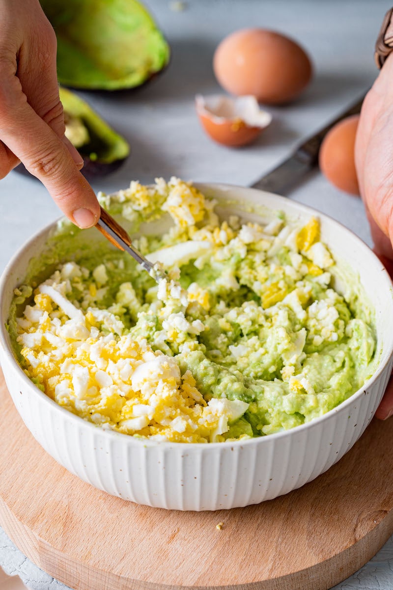 Die zerdrückten gekochten Eiern werden mit der Avocado-Joghurt-Creme vermischt.