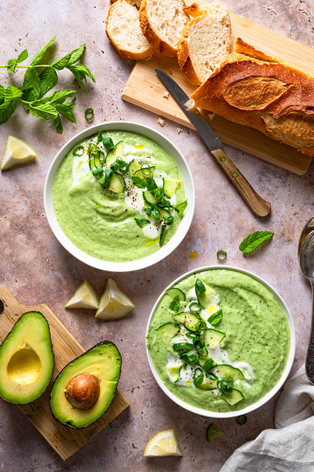 Kalte Gurken Avocado Suppe in zwei Schüsseln mit Gurke und Frühlingszwiebeln dekoriert.