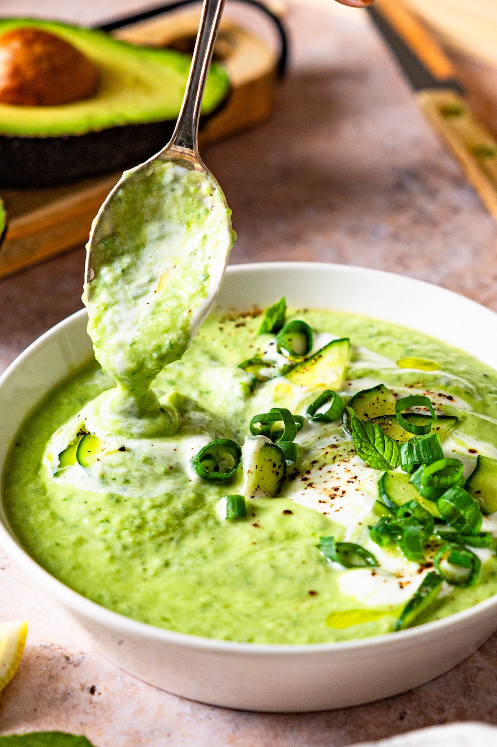 Kalte Gurken-Avocado-Suppe läuft vom Löffel in eine Schüssel.