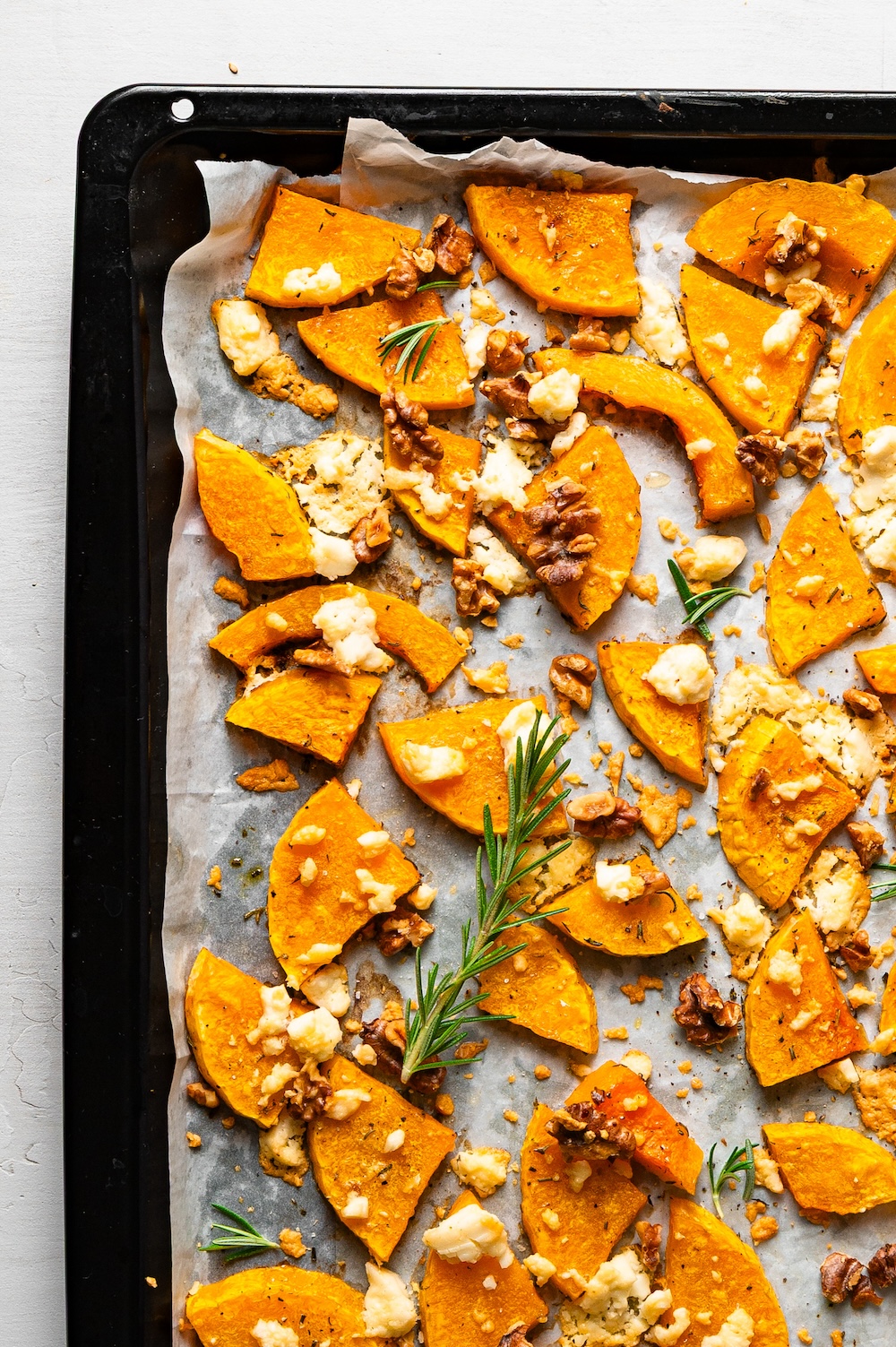 Butternut-Kürbis mit Feta, Walnüssen und Rosmarin auf einem Blech gebacken.