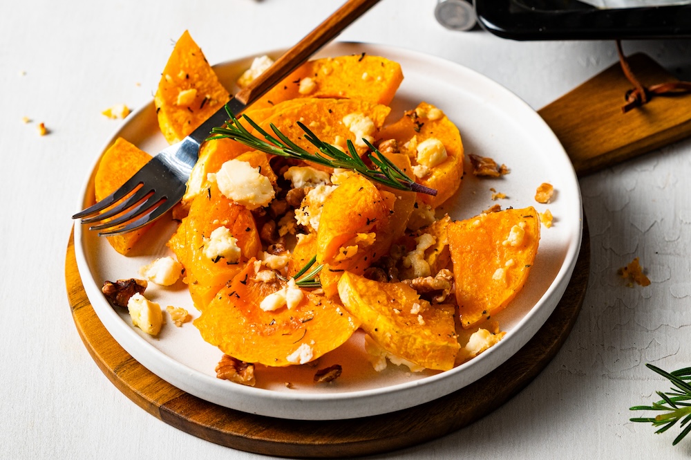 Gebackene Butternut-Kürbis-Stücke mit Feta auf einem Teller.