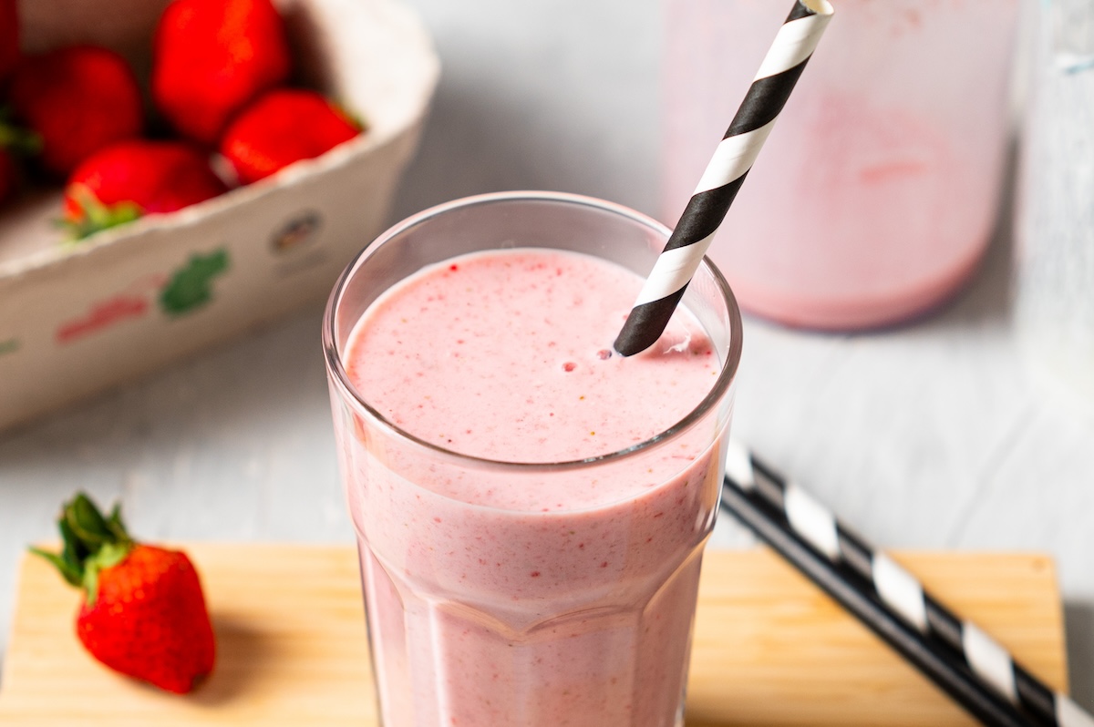 Erdbeer-Kefir-Shake in einem Glas mit schwarz-weißem Papierstrohhalm.