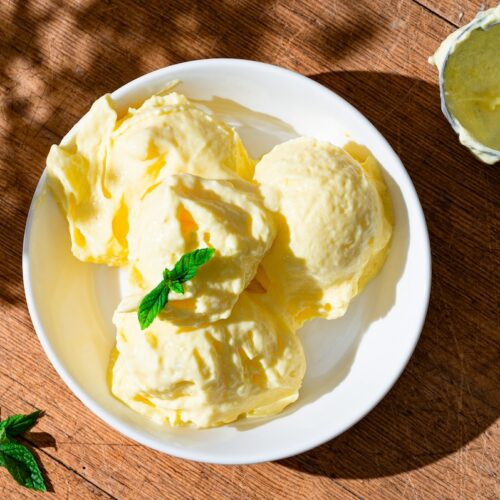 Gesundes Mango-Hüttenkäse-Eis mit Minze dekoriert.