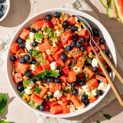 Melonen-Feta-Salat mit Heidelbeeren, Walnüssen und Minze in einer Schüssel.